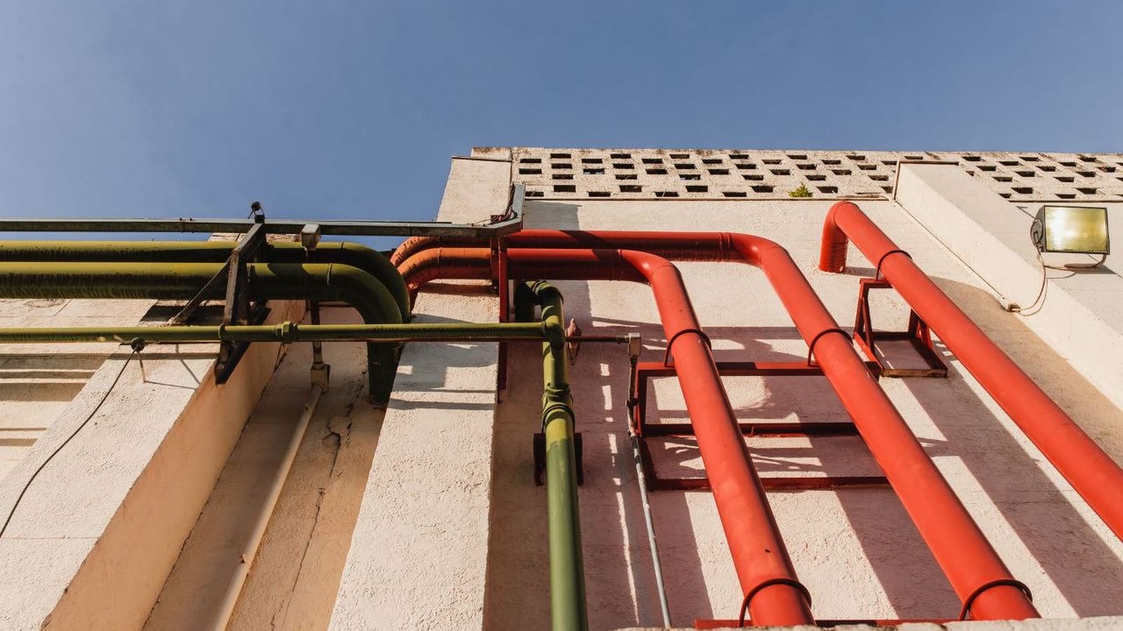 Tuberías rojas de sistema contra incendio corriendo por la fachada de un edificio industrial
